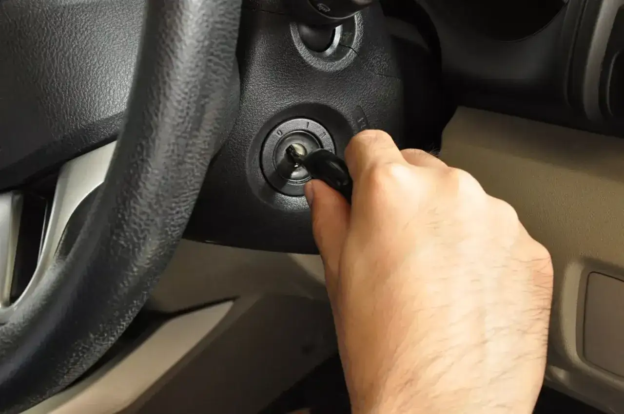 Main tenant insère la clé dans le contact, espérant démarrer la voiture malgré un symptôme de démarreur fatigué.