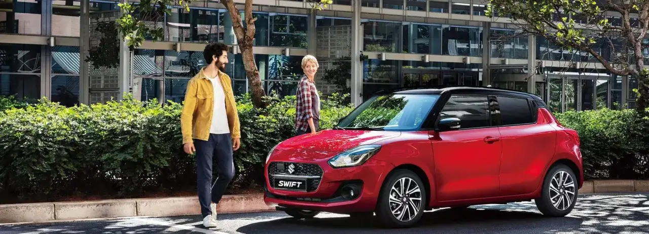 Un couple admire sa nouvelle Suzuki Swift rouge, pr&ecirc;te pour son rodage voiture.