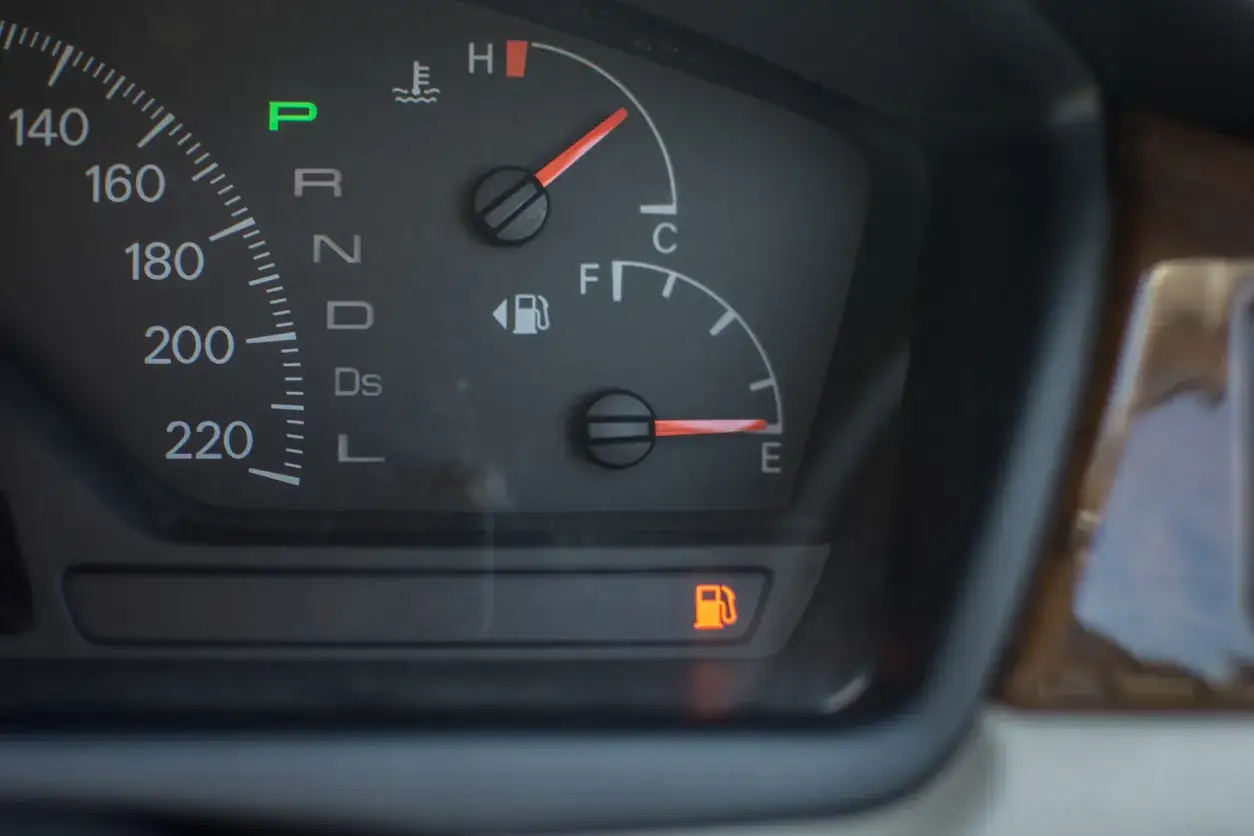 Le tableau de bord indique un niveau de carburant tr&egrave;s bas, la voyant essence est allum&eacute;. La voiture est en mode parking (P).