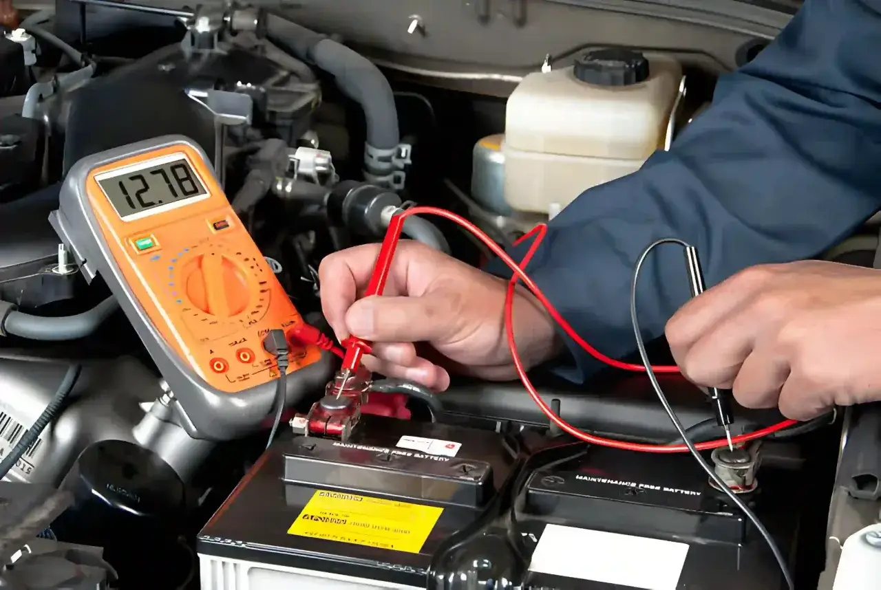 Diagnostic d'un probl&egrave;me batterie voiture avec un multim&egrave;tre affichant 12.78V. Un m&eacute;canicien teste la tension de la batterie.