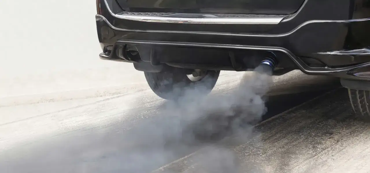 Grosse voiture noire crachant de la fumée noire à l'accélération. C'est un signe typique d'une voiture qui fume noir à l'accélération diesel.