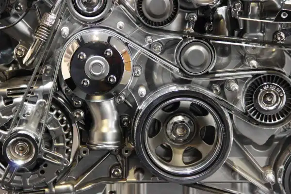 Détail mécanique d'un moteur, avec la courroie de distribution d'un C4 Picasso bien visible, entourée de poulies chromées.