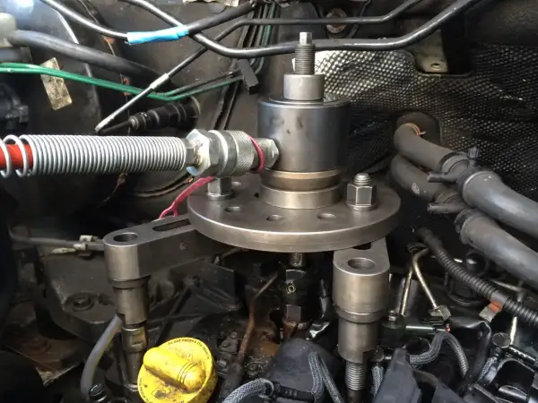 Outil pour comment enlever un injecteur grippé sans extracteur. Le dispositif est fixé sur le moteur, prêt à extraire l'injecteur récalcitrant.