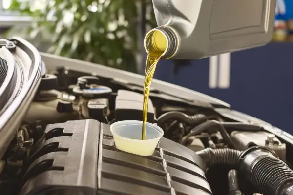 Vidange 208 essence : de l'huile neuve est versée dans un petit récipient sur le moteur d'une voiture.