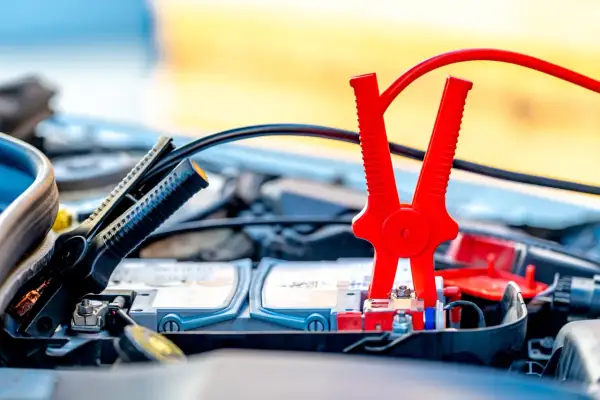 Pinces rouges et noires connectées à la batterie pour démarrer une voiture essence ou diesel.
