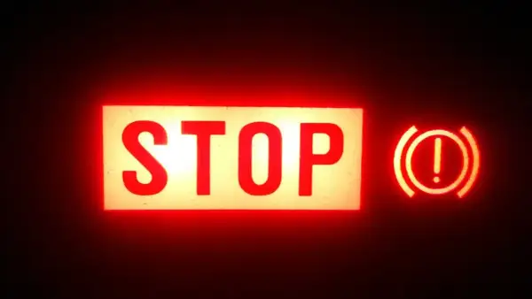 Voyant rouge "STOP" allumé, avec le symbole du frein à main activé.