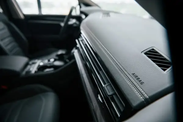 Vue intérieure d'un Peugeot Expert. Le tableau de bord en cuir noir avec surpiqûres blanches et l'inscription "AIRBAG" sont visibles. L'emplacement du calculateur airbag est ici.